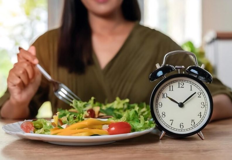 [freepicdownloader.com]-intermittent-fasting-concept-closeup-alarm-clock-table-woman-eating-hea-medium